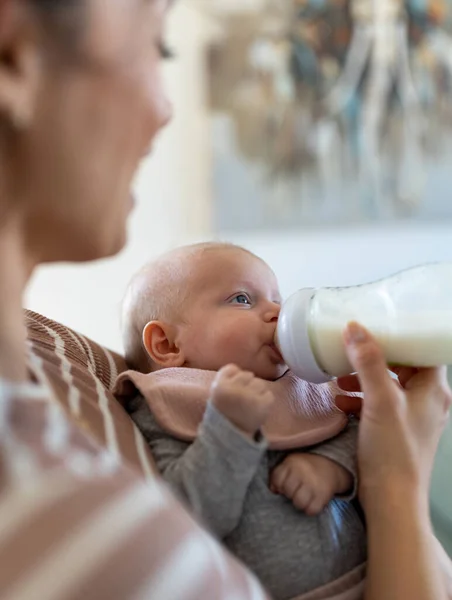 若いです母親は新生児にミルクを与えますボトルから自宅 — ストック写真