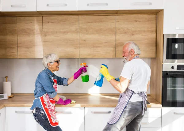 Ώριμο Ζευγάρι Κάνει Δουλειές Μαζί Στην Κουζίνα Παίζει Μπουκάλια Σπρέι — Φωτογραφία Αρχείου