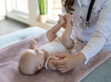 Şirin bir bebeği muayene eden genç bir doktor.