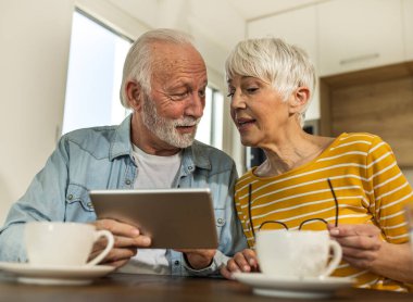 Son sınıf çifti yemek masasında oturup tablete bakıyor, internette sörf yapıyor. 