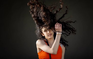 Güzel kıvırcık saçlı esmer kız stüdyoda zıplıyor.