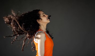 Güzel kıvırcık saçlı esmer kız stüdyoda zıplıyor.