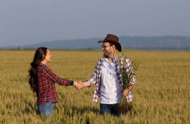 İki çiftçi yaz mevsiminde buğday tarlasında el sıkışıyor, tarım sektöründe anlaşma yapıyorlar.