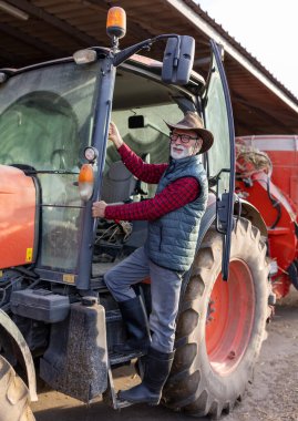 Yaşlı çiftçinin şapkalı portresi. Traktöre bin..