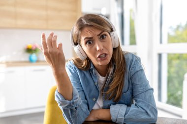 Kamerayla konuşan üzgün bir kadın, arka planda mutfağı olan bir video konferans görüşmesi.