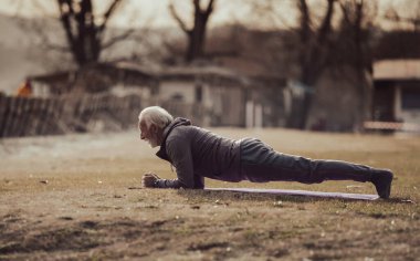 Son sınıf öğrencisi parkta yoga minderinin üzerinde kalas yapıyor. Egzersiz yaparak sağlıklı bir yaşam tarzı