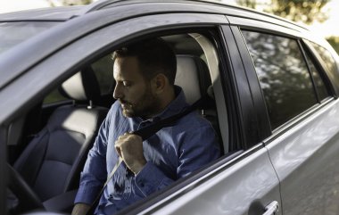 Genç bir iş adamının portresi emniyet ve hazırlık açısından sürücü koltuğuna emniyet kemerini takıyor.