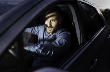 Geceleri araba kullanan yakışıklı bir adamın portresi ve başka bir aracın farları tarafından kör edilmek.