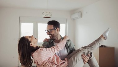 Heyecanlı genç adam, yeni dairesinin oturma odasında kız arkadaşını kaldırıyor, birlikte yaşamaya başlıyor, aile hayatına başlıyor.