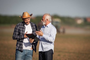 Senyor işadamı yetişkin çiftçilerle tarımsal alanda iş hakkında konuşuyor.