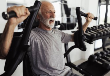 Göğüs kasları geliştirmeye kararlı emeklilerin yakın çekimleri, göğüs egzersizleri için spor aletleri kullanıyor.