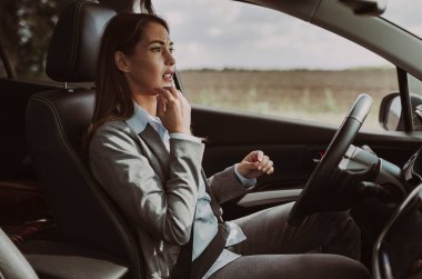 Kadın park halindeki bir araçta oturuyor ve derin düşüncelere dalıyor. Yüzündeki ifade, dışarıda eğlenirken önemli bir şey düşündüğünü gösteriyor.