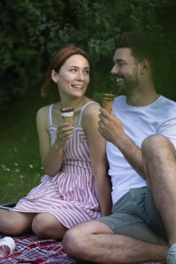 Güzel kız arkadaşı, ikisi de dondurma yerken sevgilisine sevgiyle bakıyor. Birlikte oturup parkta pikniğin tadını çıkarıyoruz.