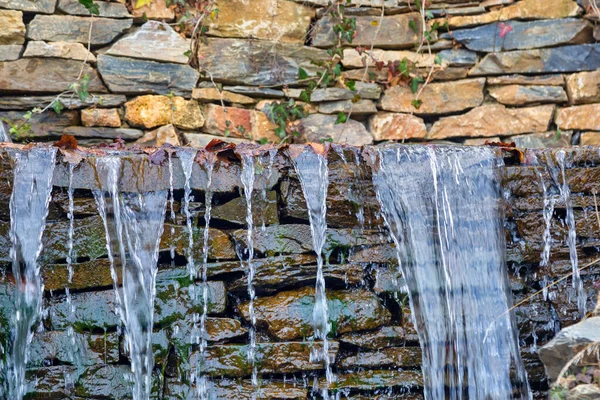 Streams of water flow over wet stones background. Water drips drop on the stones.