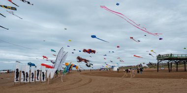 St Annes, Lancashire / Birleşik Krallık - 14 Eylül 2024: St Annes Kite Festivali. Sahile gidenler olarak gökyüzünü renkli uçurtmalar dolduruyor. Deniz kenarındaki yıllık uçurtma festivalinin tadını çıkarıyorlar.