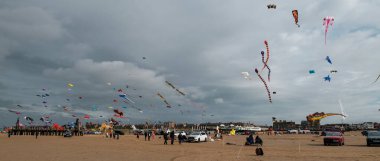 St Annes, Lancashire / Birleşik Krallık - 14 Eylül 2024: St Annes Kite Festivali. Canlı renkli uçurtmalar sahile gidenler deniz kenarında keyifli bir günün tadını çıkarırken gökyüzünü dolduruyor..