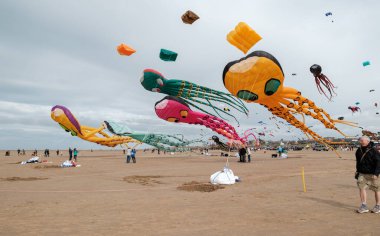 St Annes, Lancashire/United Kingdom - September 14 2024: St Annes Kite Festival. A vibrant display of colorful kites fills the sky as beachgoers enjoy a lively day by the seaside. clipart