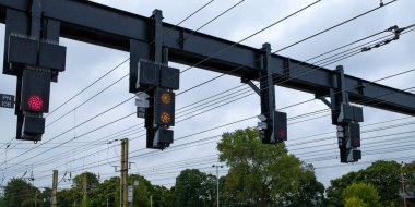 Overhead railway signals against a cloudy sky, guiding trains on their journey. clipart