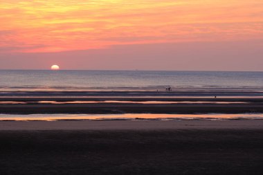 Sahilde sakin bir gün batımı. Gelgit düzlükleri ve uzak ufukları var..