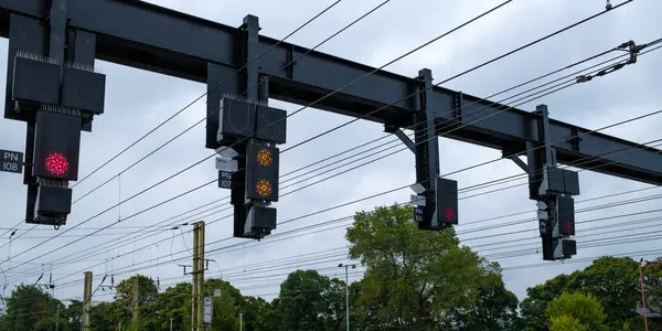 stock image Overhead railway signals against a cloudy sky, guiding trains on their journey.