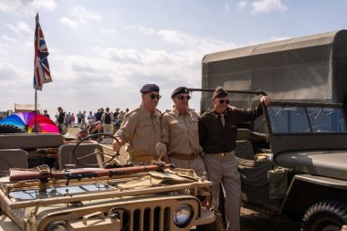 Lytham, Lancashire, Birleşik Krallık - 16 Ağustos 2025: Lytham Wartime Weekend, yıllık tarihi yeniden canlandırma etkinliği sırasında eski ordu araçlarıyla poz veren üç adam gördü..