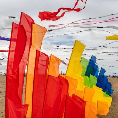 Vibrant flags in a rainbow of colors fly in the wind, symbolizing diversity, celebration, and unity.