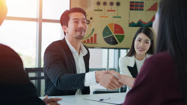 Asian male and female hands handshake. Business partners negotiate sign contract handshake. While Asian group meeting of Business male and Business female successful.