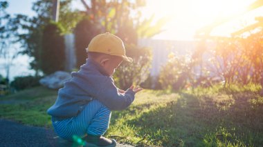 Asian cute baby boy walking play at public park outdoors with sunlight.