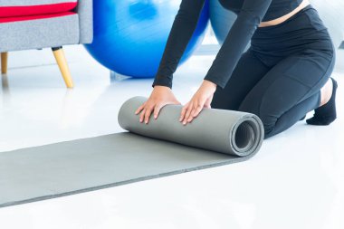 Sağlıklı yaşam tarzı kavramı. Oturma odasında egzersiz yapmadan önce sağlıklı bir kadının yoga minderini hazırlamasını sağla.
