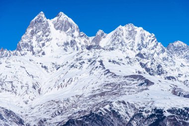 Kafkasya 'daki Ushba zirvesi kışın karla kaplı ve Mestia Svaneti Georgia' da mavi gökyüzü