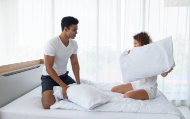 Güzel bir çift yatak odasında uyandıktan sonra yastıkla kavga ederek eğleniyor..