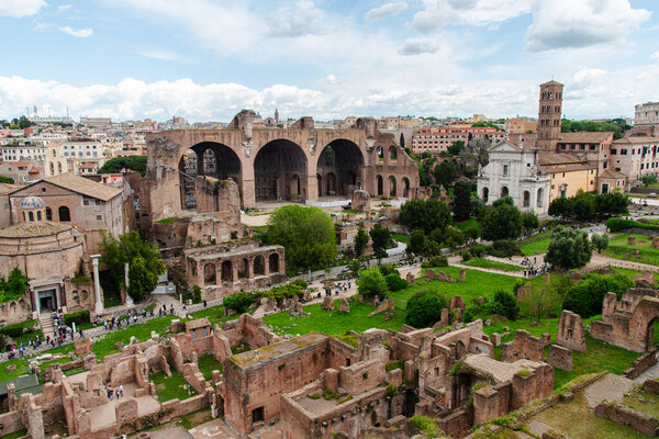An expansive aerial view over the Roman Forum, capturing the ruins and architectural remnants that narrate the story of ancient Rome amidst a modern city.