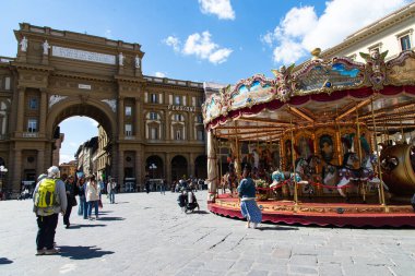 Floransa, İtalya-19 Nisan 2024: Turistler Floransa 'daki Piazza della β bblica' da renkli bir klasik atlıkarınca ve tarihi mimarinin yer aldığı güneşli bir günün tadını çıkarıyorlar..