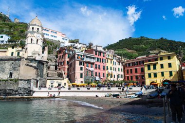 Cinque Terre, İtalya-20 Nisan 2024: Canlı binalar, tarihi bir kilise ve güneşli bir günün keyfini çıkaran turistlerin yer aldığı Vernazza 'nın Cinque Terre' deki liman manzarası.