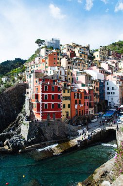 Cinque Terre, İtalya-20 Nisan 2024: Açık mavi Akdeniz manzaralı, İtalya 'nın Cinque Terre kentindeki Riomaggiore kayalıklarına tünemiş canlı evler.