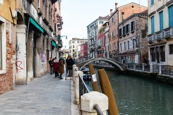 stock image Venice, Italy-April 24, 2024: A vibrant street scene in Venice, Italy, featuring a canal, bridge, and colorful buildings, with locals and tourists enjoying a stroll.