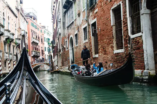 Venedik, İtalya-24 Nisan 2024: Turistler Venedik, İtalya 'da tarihi binalar ve canlı mimari ile çevrili dar bir kanalda gondol yolculuğunun keyfini çıkarıyorlar.