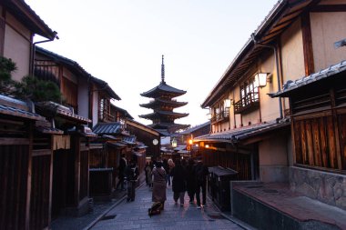 Kyoto, Japonya, 11 Şubat 2025: Aydınlanmış Yasaka Pagoda 'ya doğru geleneksel Kyoto caddesinde yürüyen turistlerin akşam manzarası.
