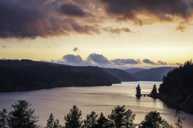 Vyrnwy Gölü, Galler 'in ortasında, gün batımında olağanüstü doğal güzellikte bir alan. Turuncu gökyüzü gölün sakin suyuna yansıyor.