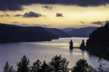 Vyrnwy Gölü, Galler 'in ortasında, gün batımında olağanüstü doğal güzellikte bir alan. Turuncu gökyüzü gölün sakin suyuna yansıyor.