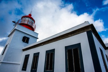 Mavi gökyüzüne karşı silueti olan eski kırmızı ve beyaz deniz feneri Kuzey Madeira Portekiz 'de Ponta do Pargo