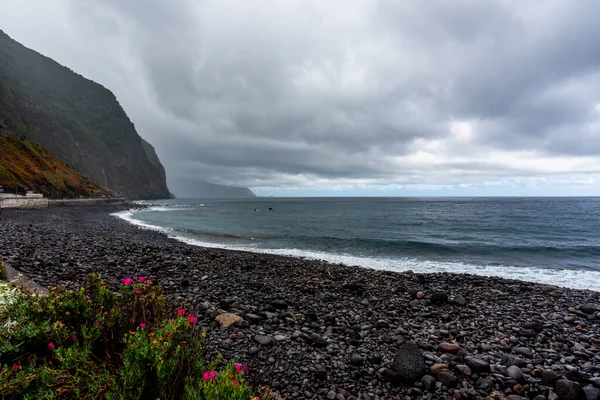 stock image the atlantic ocean crashes on the rocks and coast of Madeira on a cloudy day with calm sea and gray clouds in the North coast of Madeira near Seixal Madeira Portugal