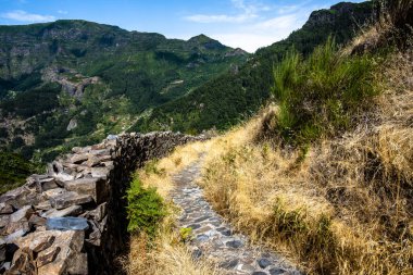 mountainous path between peaks covered with greenery and blue sky in Madeira Portugal