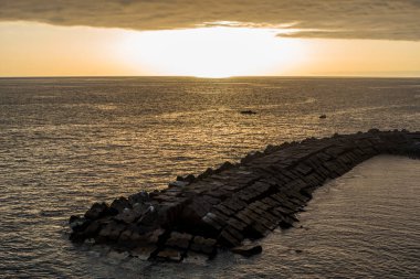 sunset over the atlantic ocean with the bay and the rocks , photographed from the rocks of the bay of Porto do Sol in Madeira Portugal