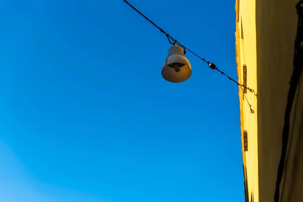 Uliczna Lampa Żółtą Ścianą Błękitne Niebo Uliczne Światło Wiszące Drutu — Zdjęcie stockowe