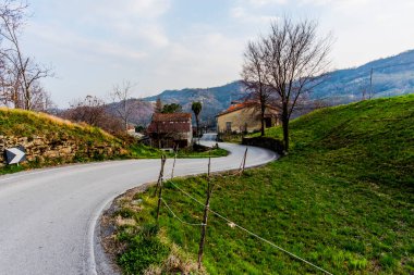 Vicenza tepeleri ile Vallonara Vicenza Veneto İtalya 'da tuğla evleri olan bir köy arasında asfalt yol rüzgarları esiyor.