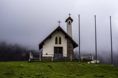 İtalya 'da Rovereto Trentino' da bulutlarla kaplı dağlardaki küçük dağlık kilise.