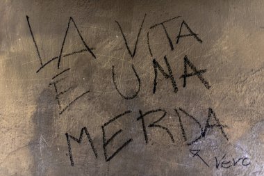 graffiti written on wall saying life is shit black graffiti on yellow wall in Treviso Veneto Italy