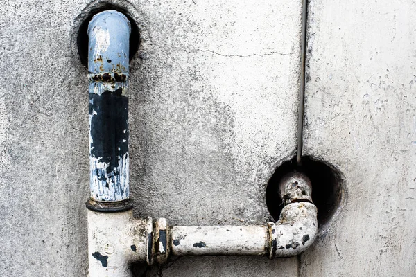 rusted and weathered blue and yellow pipes entering the concrete wall in Treviso Veneto Italy