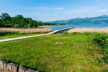 Lombard kıyılarından Maggiore Gölü 'nün panoramik manzarası. Ağaçlar ve Maggiore Gölü' nde balıkçı tekneleri olan büyüleyici küçük limanlar. Varese Lombardy İtalya 'da.